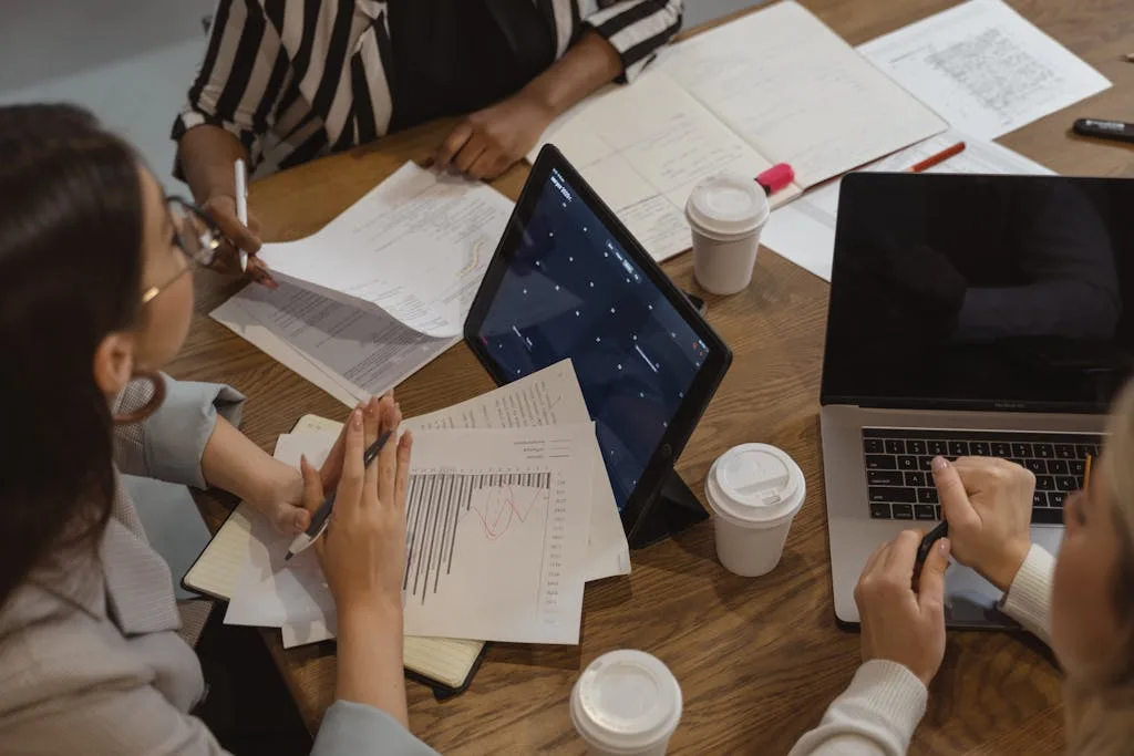 Business team collaborating with laptops and documents in a meeting, showcasing teamwork and cooperation.