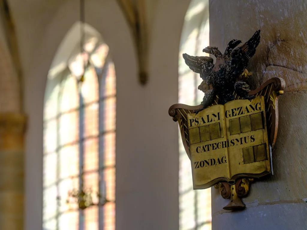 Gothic church interior in Naarden, featuring sunlight filtering through stained glass windows and a psalm board.